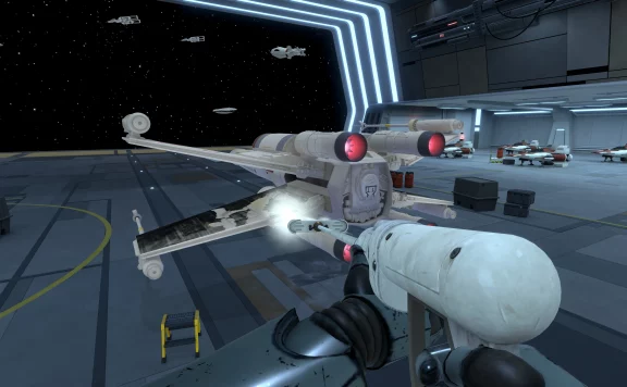 First-person view from a pilot in a white spacefighter, aiming a forward cannon inside a futuristic hangar with ships docked along the bay.
