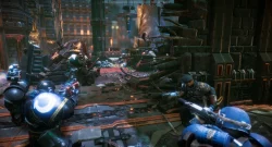 Armored soldiers in blue suits fire rifles in a ruined, chain-filled chamber with rubble and glowing blue accents.