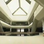 Wide interior atrium with a geometric skylight ceiling and circular balcony railings surrounding the open space.