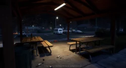 Nighttime scene under a wooden pavilion with picnic tables, a nearby parking lot, and a white van in the distance; scattered litter on the ground.
