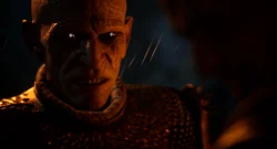 Close-up of a snarling zombie-like creature with orange lighting and glowing eyes.