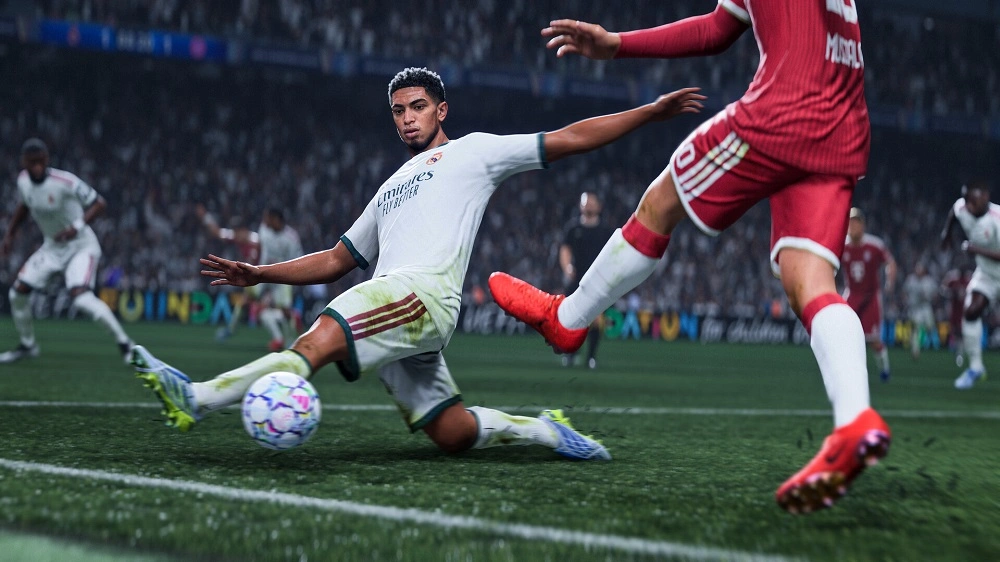 Soccer player in white slides to block the ball as a red-clad opponent kicks toward him on a packed stadium field