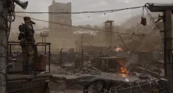 A soldier stands on a raised platform watching a desolate, smoke-filled city with barbed wire in the foreground and rubble around.
