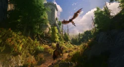 Rider on horseback follows a sunlit forest path as a large eagle soars above near a stone tower on the left.