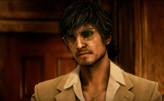 Man wearing a brown blazer and open-collar shirt with a gold chain, sporting sunglasses, in a wood-paneled setting.